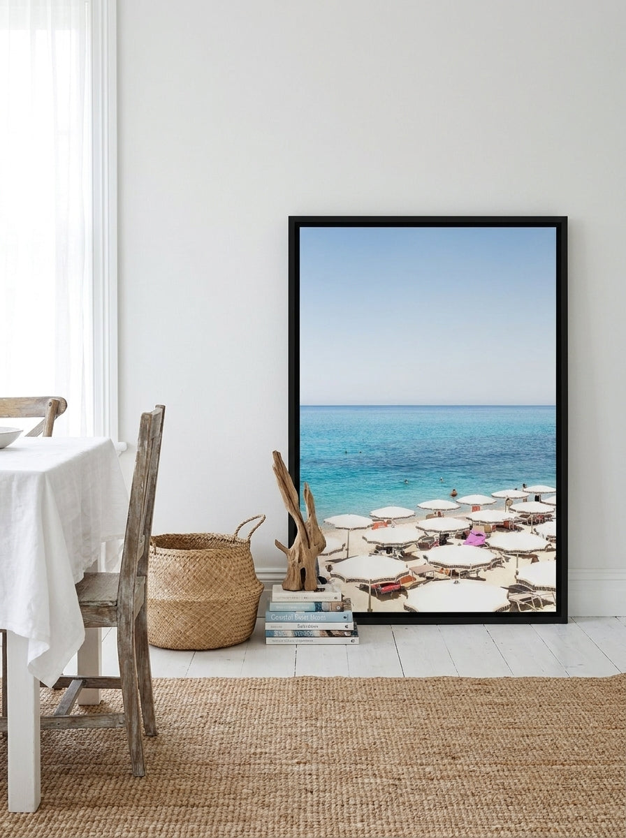 Canvas wall art with a black surround leaning against the wall in a coastal dining room