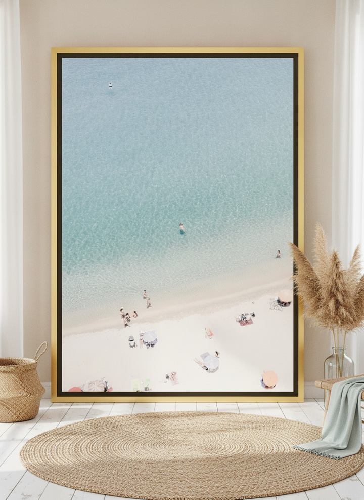 Oversized statement canvas wall art with a gold leaf surround leaning against the wall in a coastal dining room