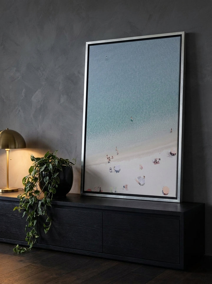 Canvas wall art with a silver leaf surround standing on a console in a moody living room