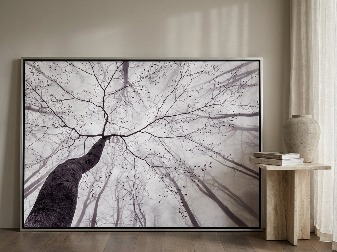 Oversized statement canvas wall art with a silver leaf surround leaning against the wall in a luxe living room