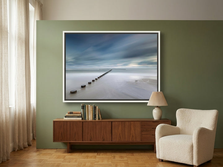 Oversized statement canvas wall art with a white surround styled on the wall in a mid-century living room