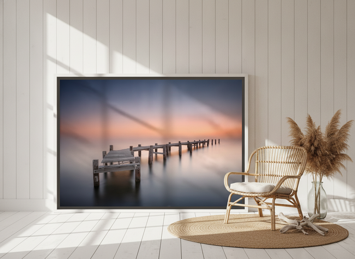 Oversized statement canvas wall art with a white surround leaning against the wall in a coastal living room