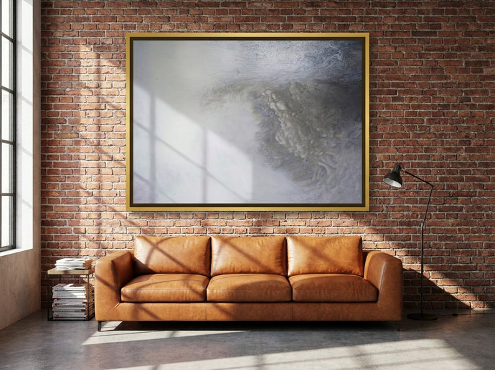 Oversized statement canvas wall art with a gold leaf surround styled on the wall in an industrial loft living room