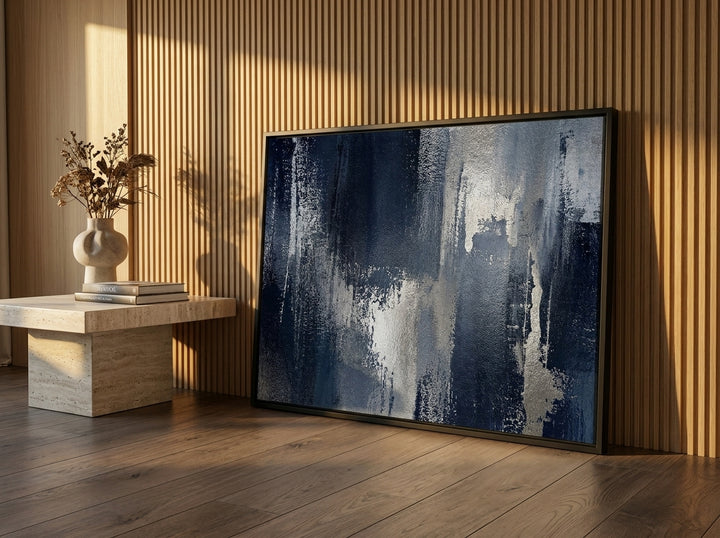 Oversized statement canvas wall art with a black surround leaning against the wall in a luxe bedroom