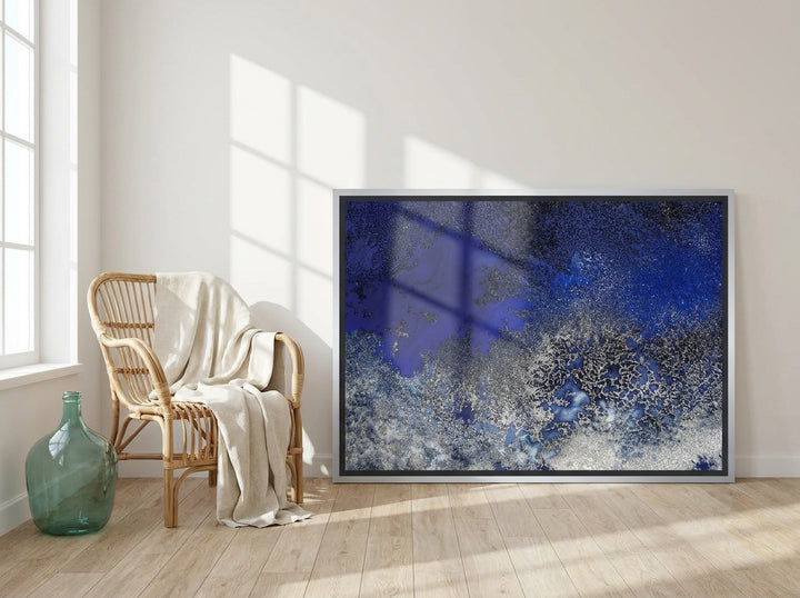 Canvas wall art with a silver leaf surround leaning against the wall in a coastal home office