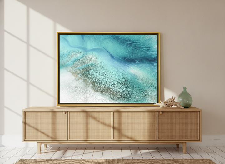 Canvas wall art with a gold leaf surround standing on a sideboard in a coastal living room