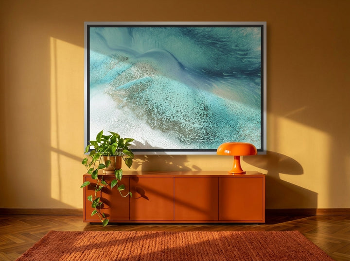 Oversized statement canvas wall art with a silver leaf surround styled on the wall in a retro 70s living room