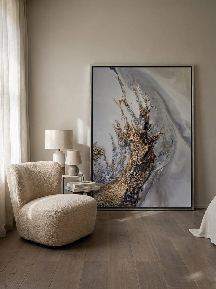 Oversized statement canvas wall art with a silver leaf surround leaning against the wall in a luxe bedroom