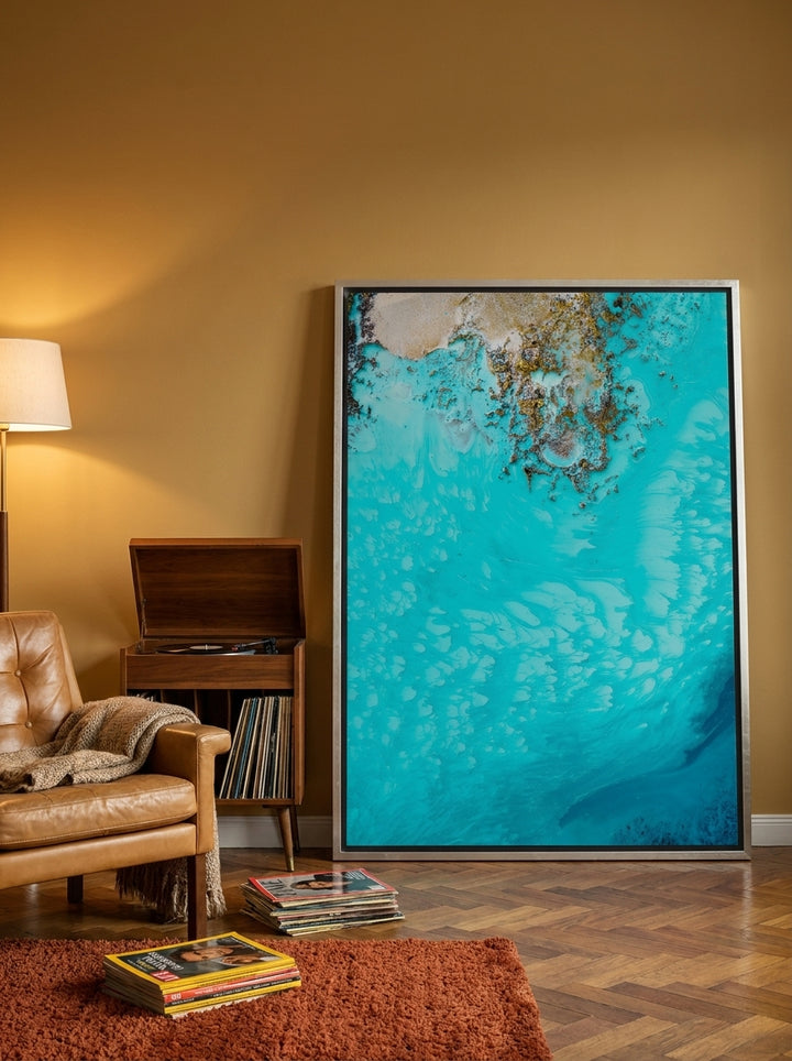 Oversized statement canvas wall art with a silver leaf surround leaning against the wall in a retro 70s living room