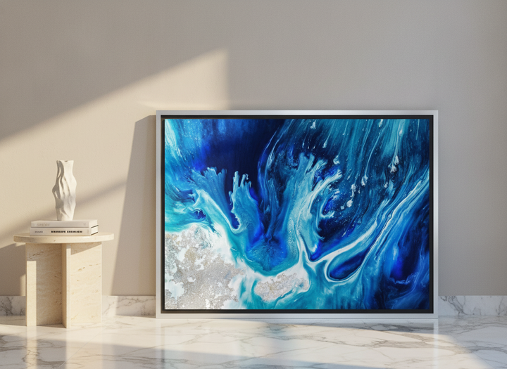 Canvas wall art with a silver leaf surround leaning against the wall in a luxe living room