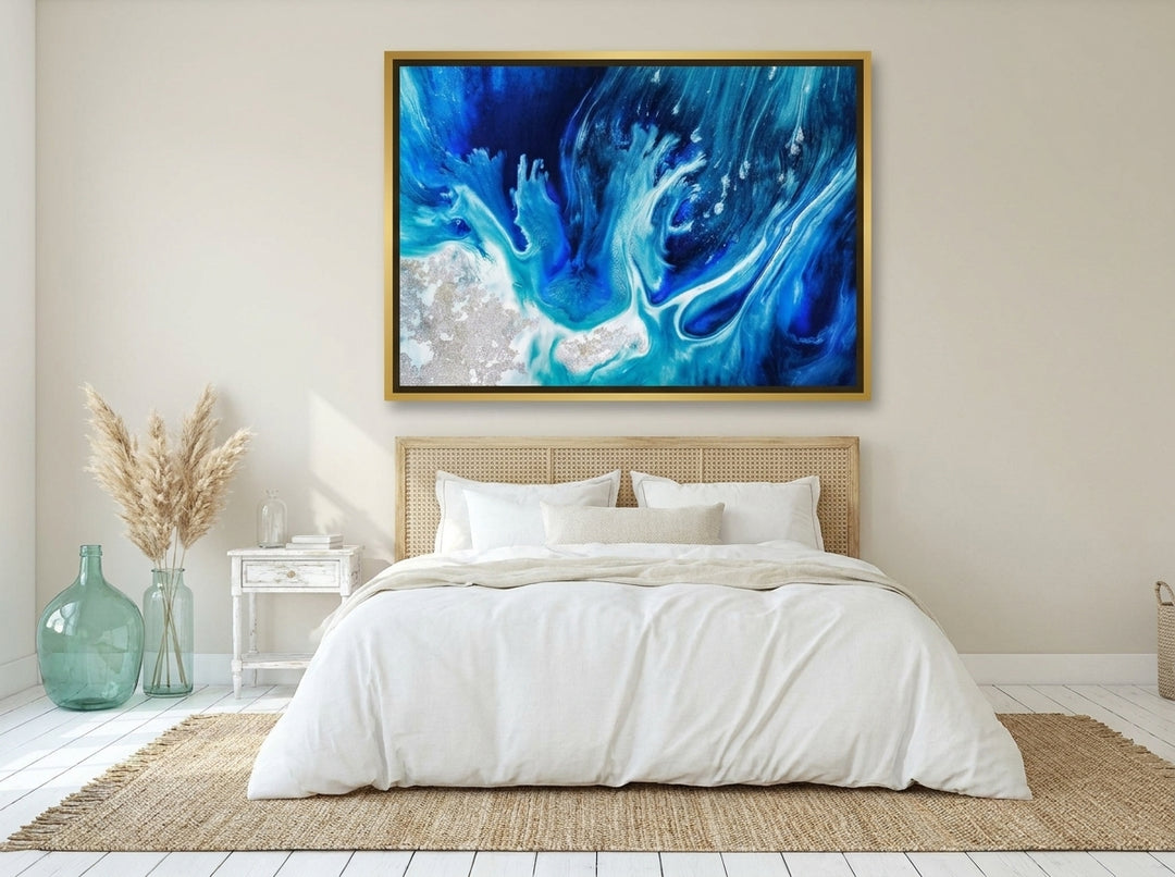 Oversized statement canvas wall art with a gold leaf surround styled on the wall in a coastal bedroom