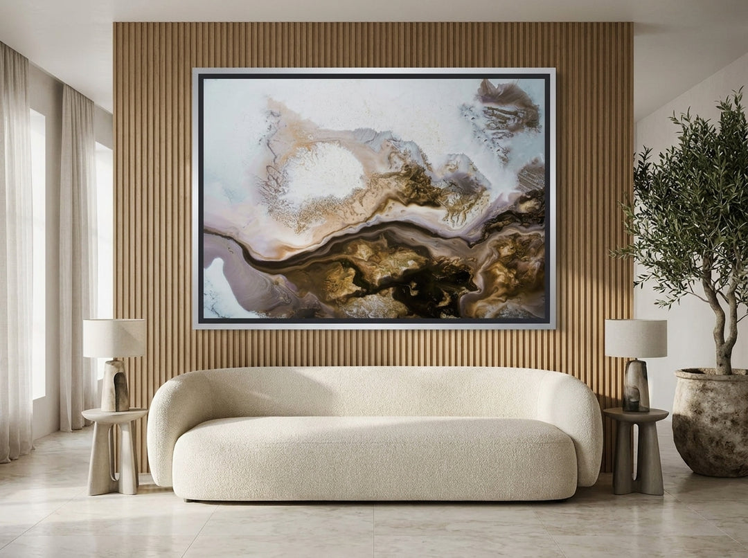 Oversized statement canvas wall art with a silver leaf surround styled on the wall in a luxe living room