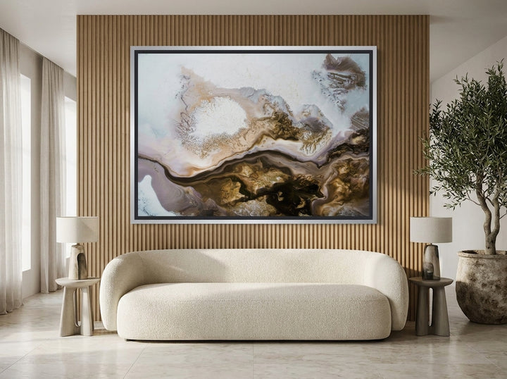 Oversized statement canvas wall art with a silver leaf surround styled on the wall in a luxe living room