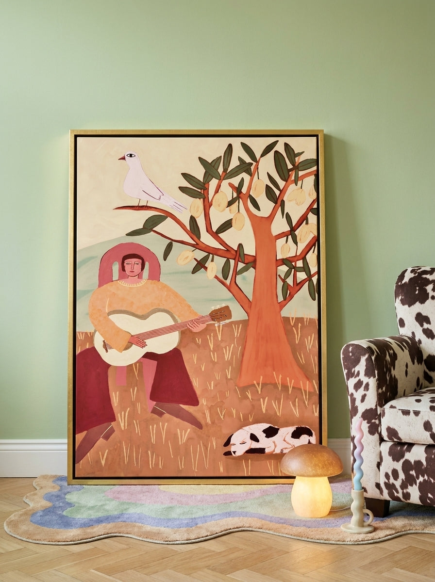 Canvas wall art with a gold leaf surround leaning against the wall in a colourful eclectic nursery