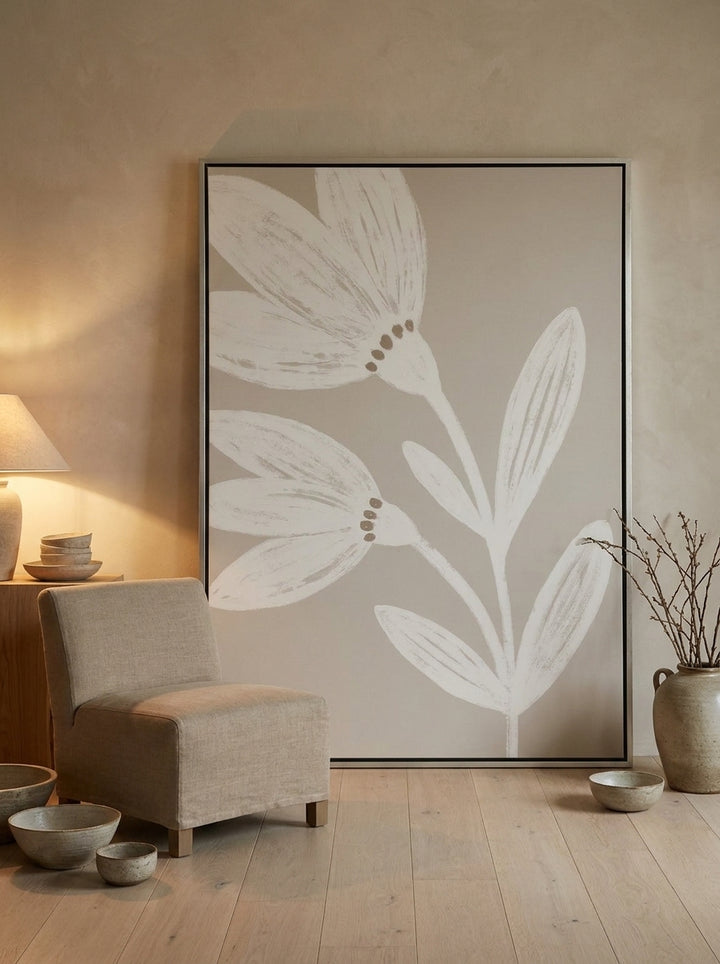 Oversized statement canvas wall art with a silver leaf surround leaning against the wall in a warm Japandi living room
