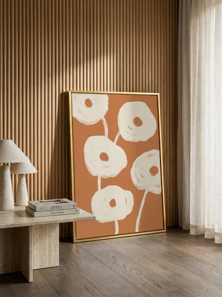 Oversized statement canvas wall art with a gold leaf surround leaning against the wall in a luxe living room