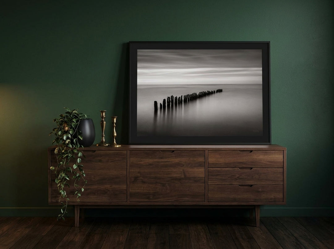 Modern wall art print standing on a sideboard in a moody living room