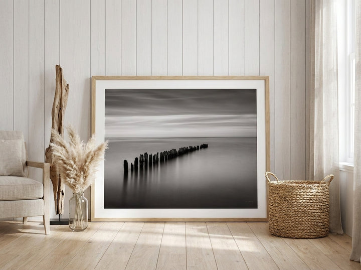 Oversized statement modern wall art print leaning against the wall in a coastal bedroom