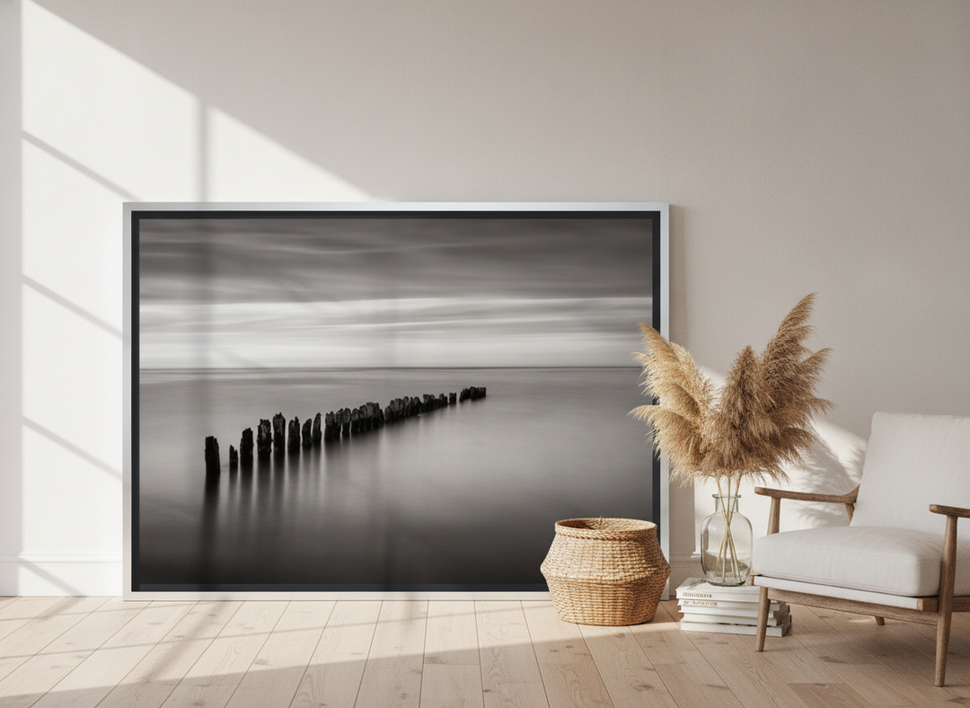 Oversized statement canvas wall art with a silver leaf surround leaning against the wall in a coastal bedroom