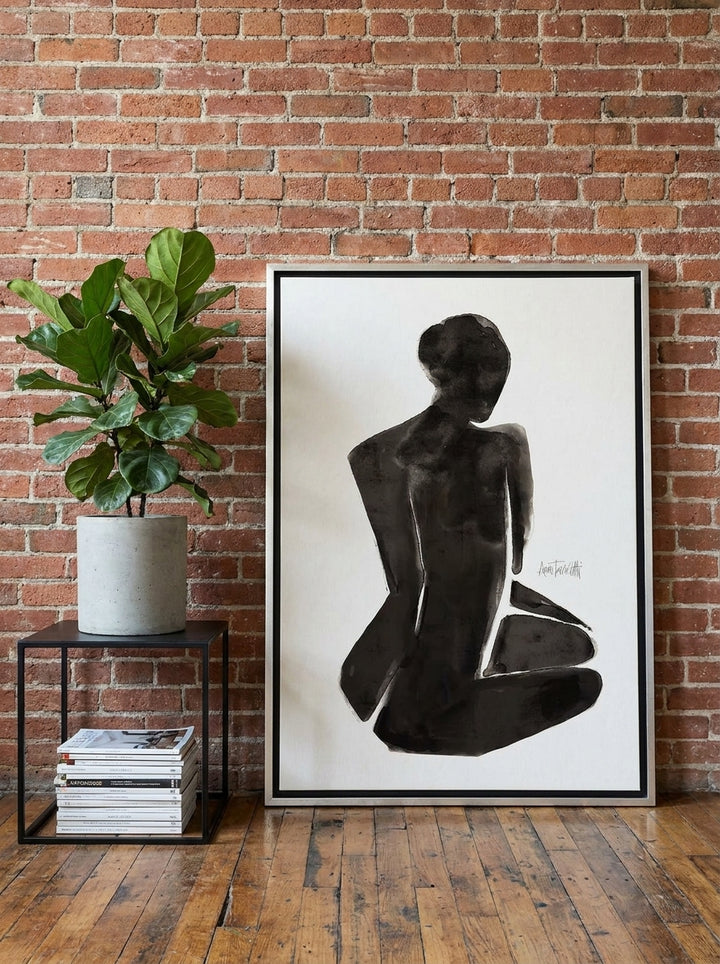 Oversized statement canvas wall art with a silver leaf surround leaning against the wall in an industrial loft living room