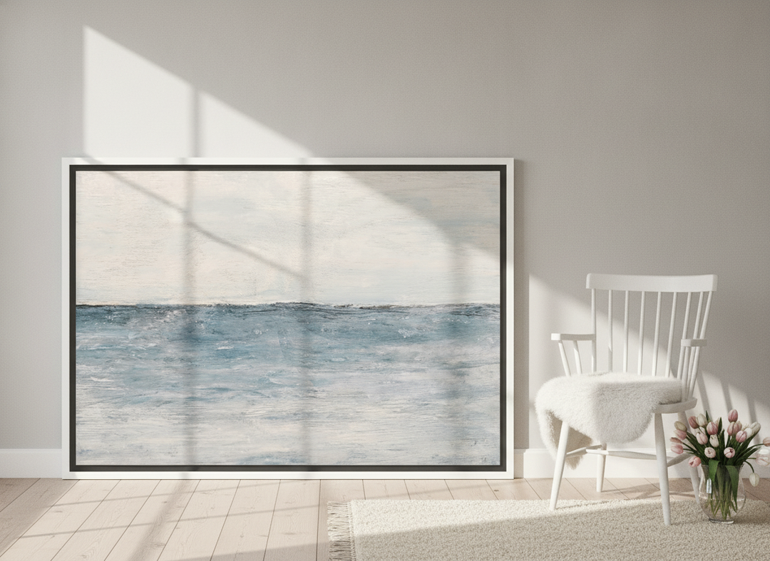 Canvas wall art with a white surround leaning against the wall in a bright Scandinavian bathroom