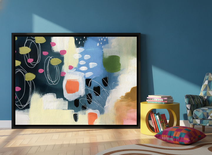 Oversized statement canvas wall art with a black surround leaning against the wall in a colourful eclectic bedroom