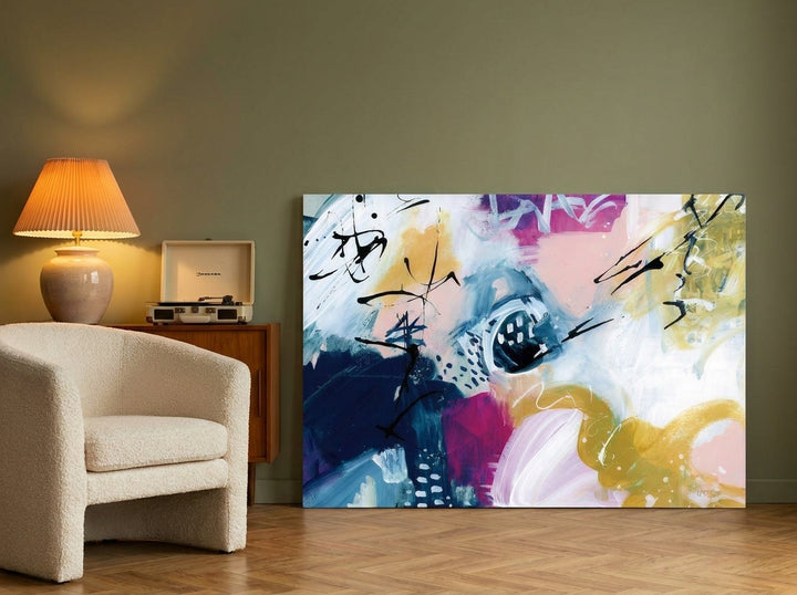 Stretched canvas wall art leaning against the wall in a mid-century living room