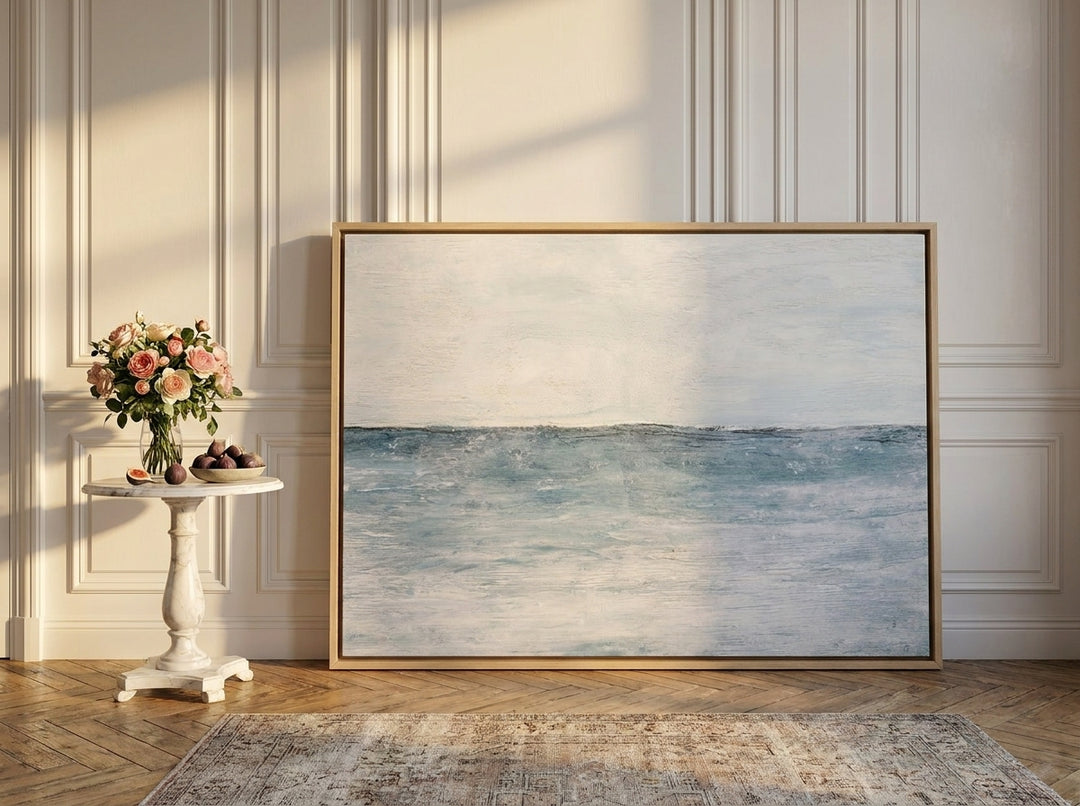 Oversized statement canvas wall art with a natural timber surround leaning against the wall in a Parisian living room