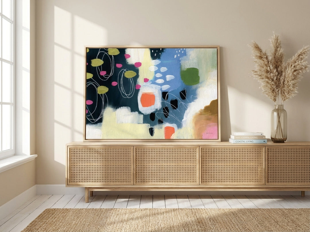 Canvas wall art with a natural timber surround standing on a sideboard in a coastal bedroom