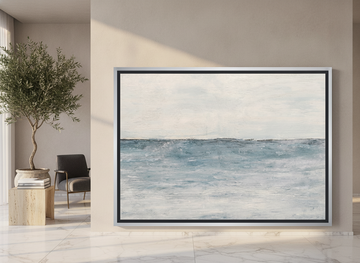 Oversized statement canvas wall art with a silver leaf surround leaning against the wall in a luxe dining room