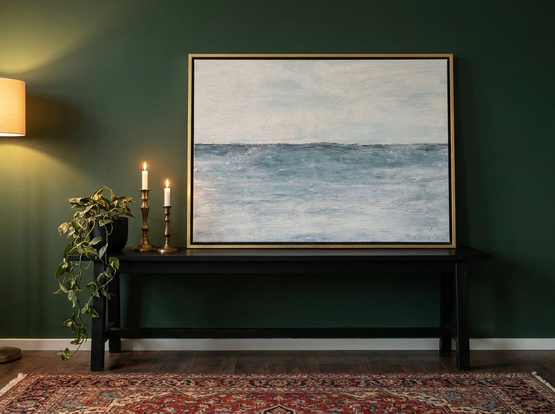 Canvas wall art with a gold leaf surround standing on a console in a moody home office