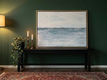 Canvas wall art with a gold leaf surround standing on a console in a moody home office