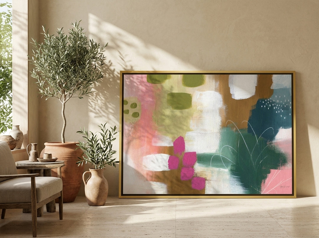 Oversized statement canvas wall art with a gold leaf surround leaning against the wall in a Mediterranean living room