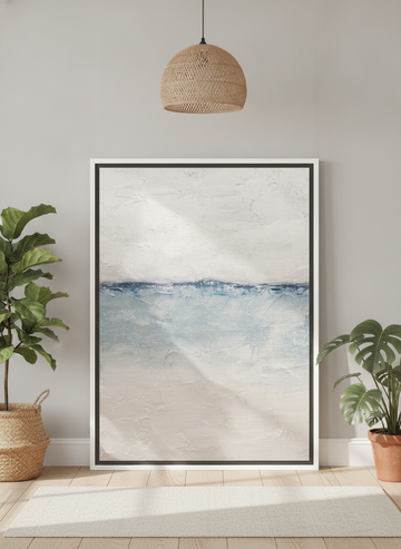 Canvas wall art with a white surround leaning against the wall in a bright Scandinavian bathroom