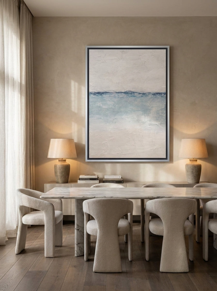 Oversized statement canvas wall art with a silver leaf surround styled on the wall in a luxe dining room