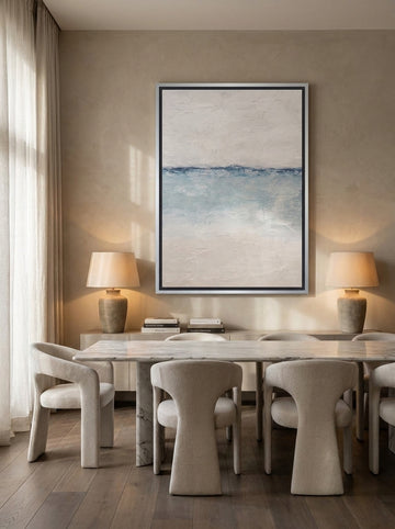 Oversized statement canvas wall art with a silver leaf surround styled on the wall in a luxe dining room