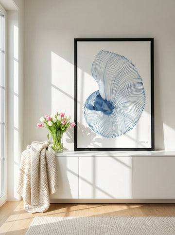 Canvas wall art with a black surround standing on a sideboard in a bright Scandinavian bathroom