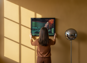 Person holding modern wall art print in a retro 70s living room