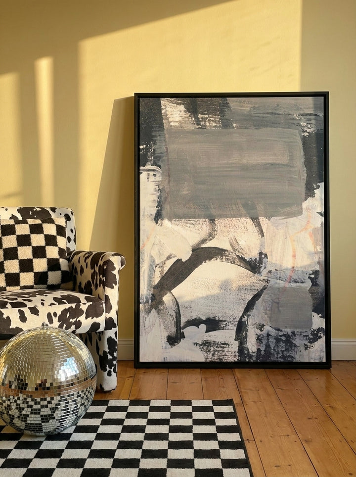 Canvas wall art with a black surround leaning against the wall in a colourful eclectic living room