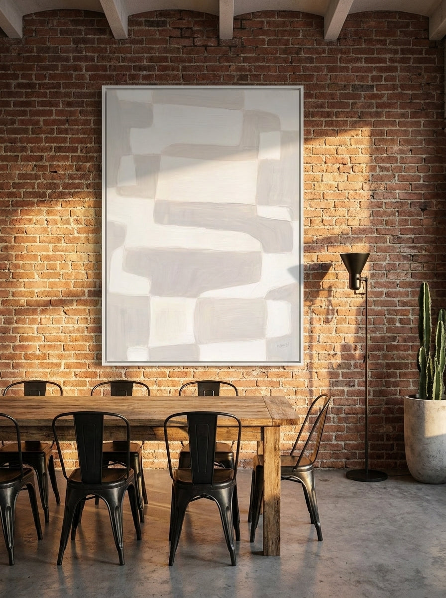 Oversized statement canvas wall art with a white surround styled on the wall in an industrial loft dining room