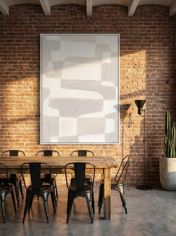 Oversized statement canvas wall art with a white surround styled on the wall in an industrial loft dining room