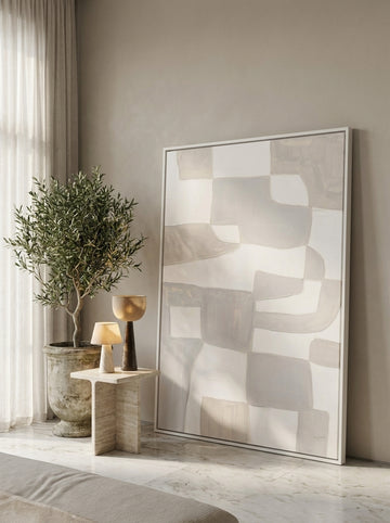 Oversized statement canvas wall art with a white surround leaning against the wall in a luxe bedroom