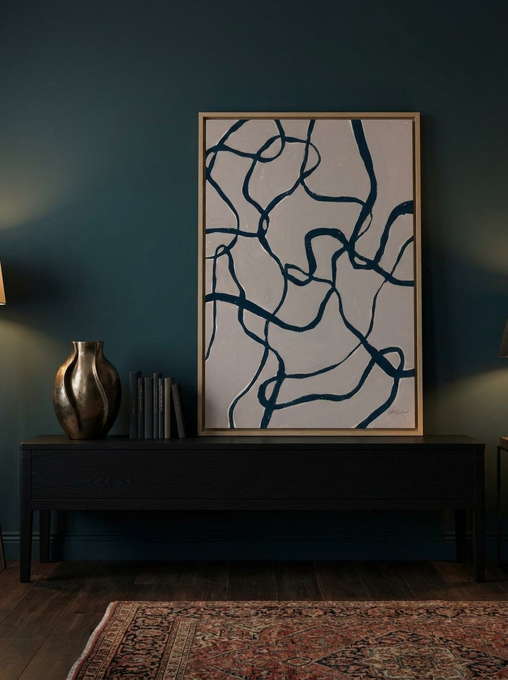 Canvas wall art with a natural timber surround standing on a console in a moody bedroom