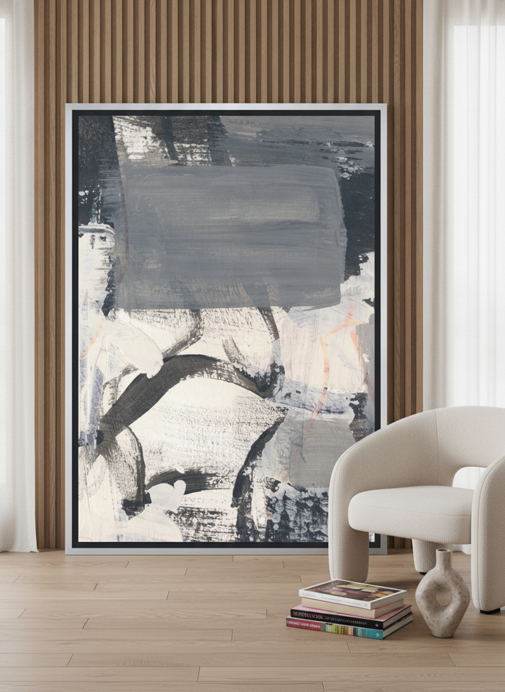 Oversized statement canvas wall art with a silver leaf surround leaning against the wall in a luxe living room