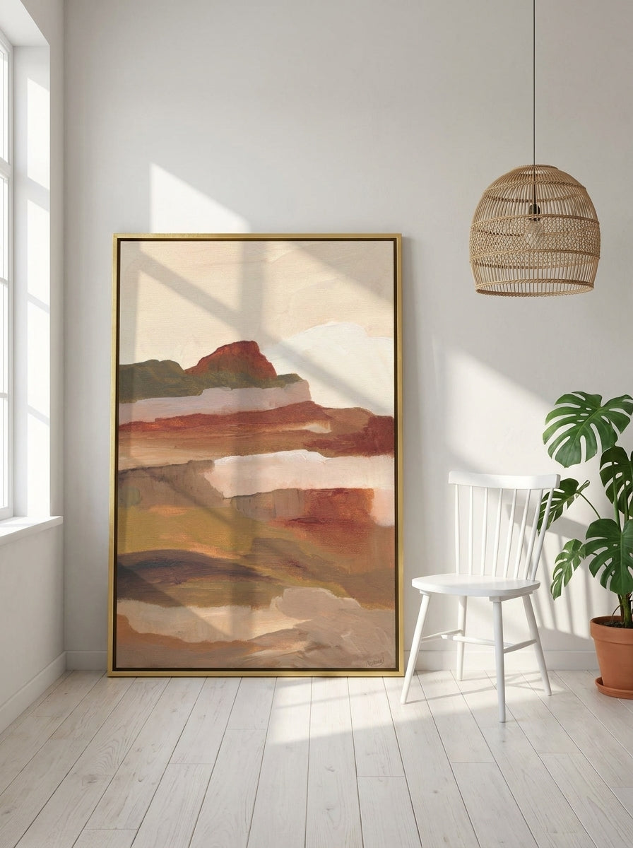 Oversized statement canvas wall art with a gold leaf surround leaning against the wall in a bright Scandinavian living room