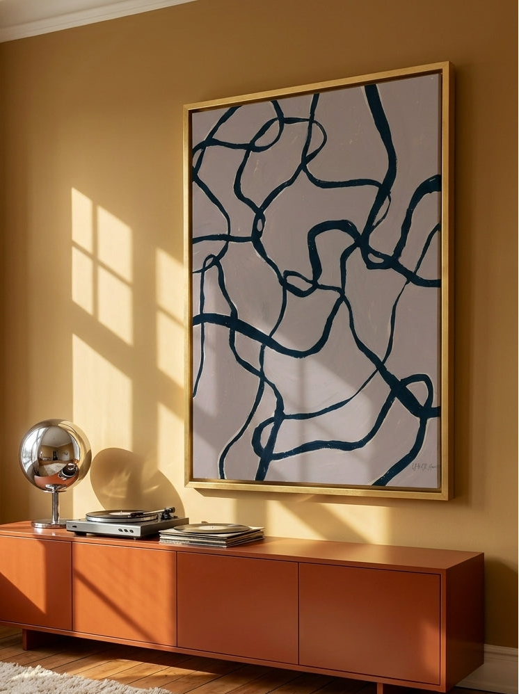 Oversized statement canvas wall art with a gold leaf surround styled on the wall in a retro 70s living room