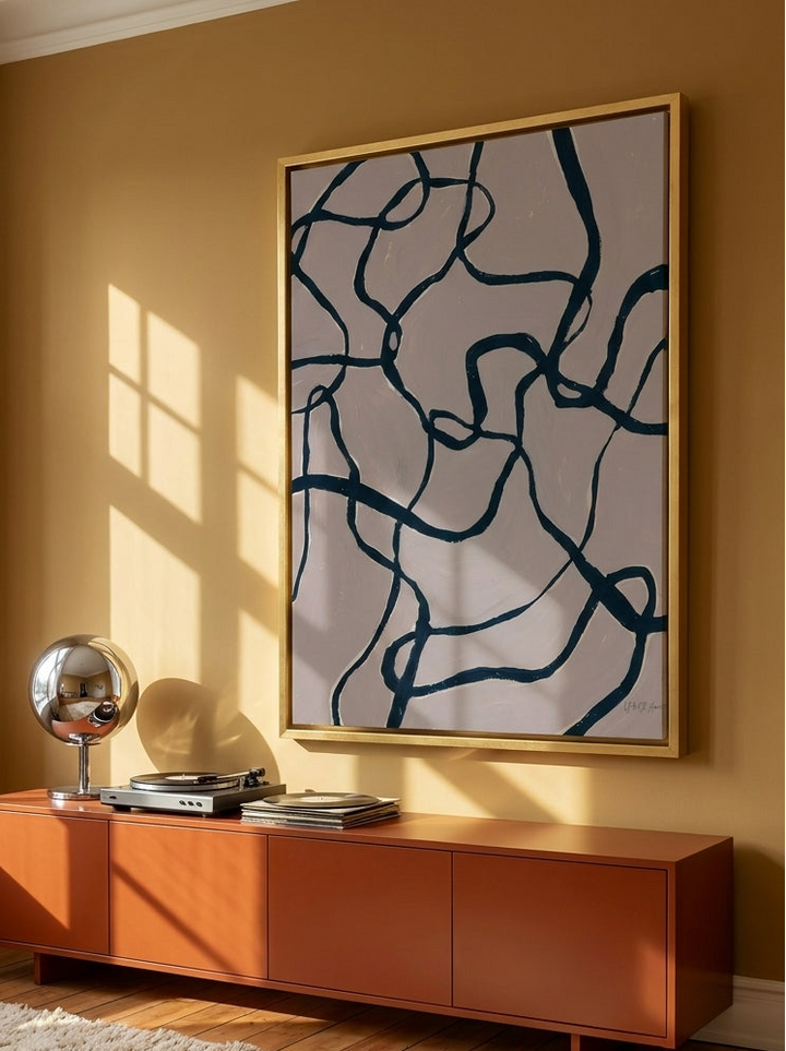 Oversized statement canvas wall art with a gold leaf surround styled on the wall in a retro 70s living room