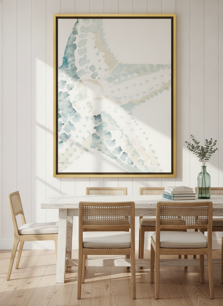 Oversized statement canvas wall art with a gold leaf surround styled on the wall in a coastal dining room