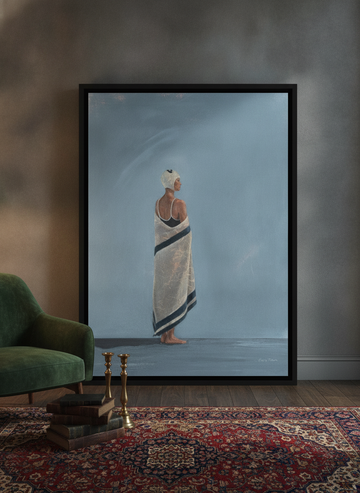 Oversized statement canvas wall art with a black surround leaning against the wall in a moody living room
