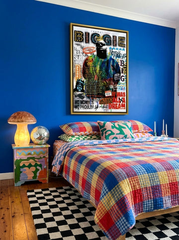 Canvas wall art with a gold leaf surround styled on the wall in a colourful eclectic bedroom